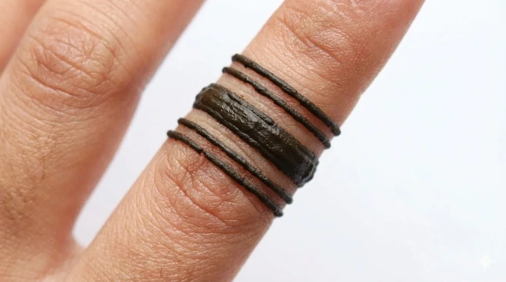 Simple finger mehndi design featuring three dark horizontal bands wrapping around the index finger like rings.