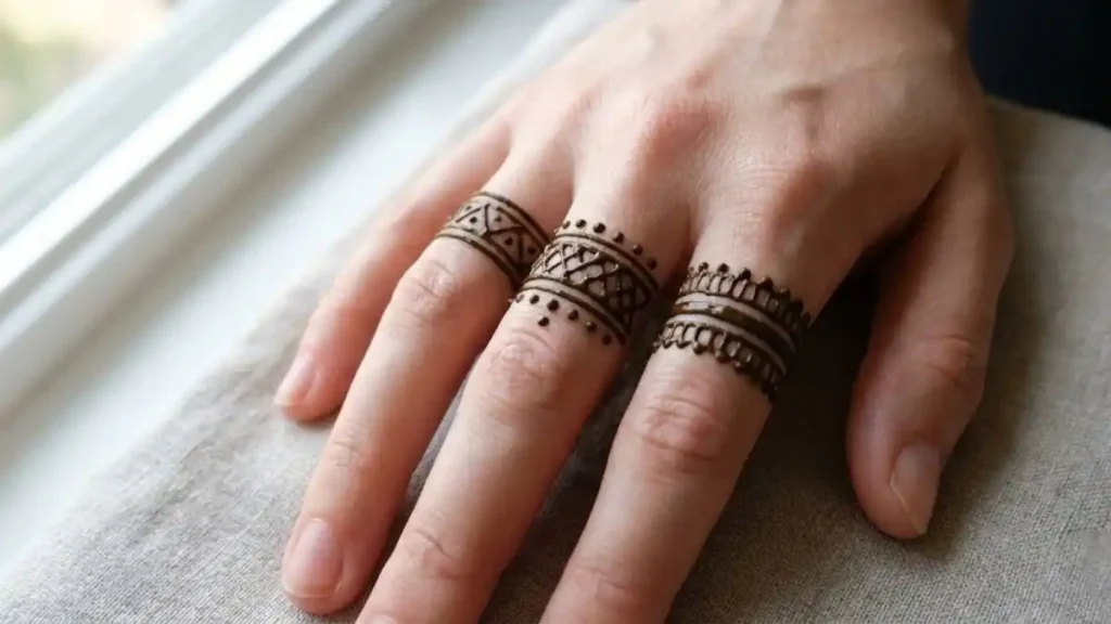 20 Stylish and Simple Back Hand Mehndi Designs 4 Minimalist henna ring bands drawn on the middle knuckles of three fingers.